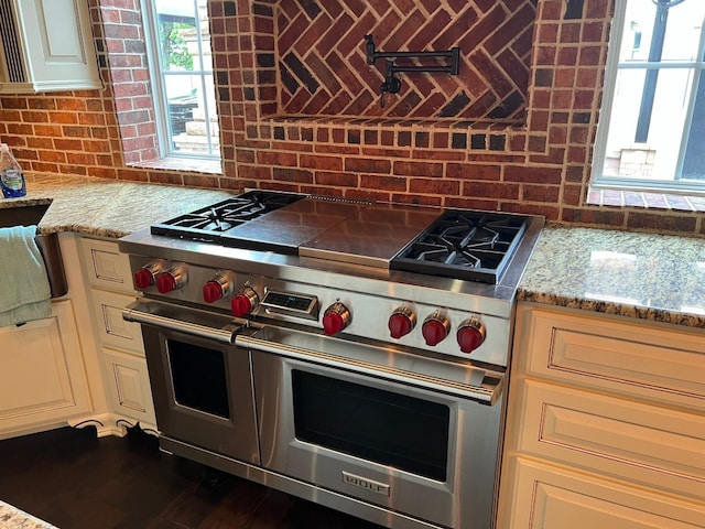 kitchen featuring double oven range, dark wood-type flooring, and light stone counters