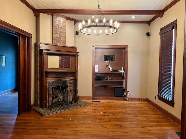 unfurnished living room featuring dark wood-type flooring, a brick fireplace, brick wall, a notable chandelier, and beam ceiling