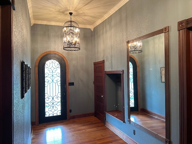 entryway with dark hardwood / wood-style flooring, crown molding, a notable chandelier, and a healthy amount of sunlight