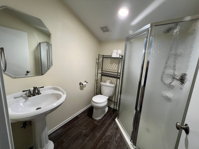 bathroom with toilet, a shower with door, and hardwood / wood-style flooring