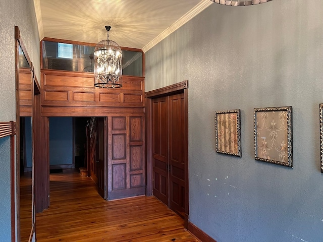 corridor with a notable chandelier, crown molding, and dark hardwood / wood-style floors