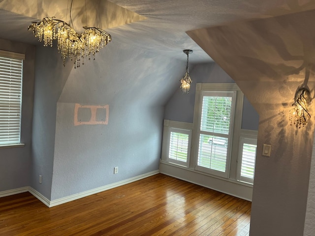 additional living space featuring a chandelier, dark wood-type flooring, and vaulted ceiling