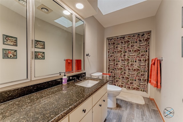 bathroom featuring a skylight, oversized vanity, toilet, and wood-type flooring