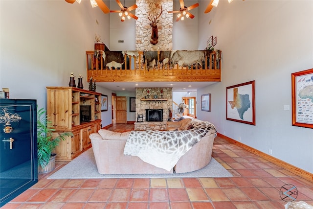 tiled living room with ceiling fan, a towering ceiling, and a fireplace