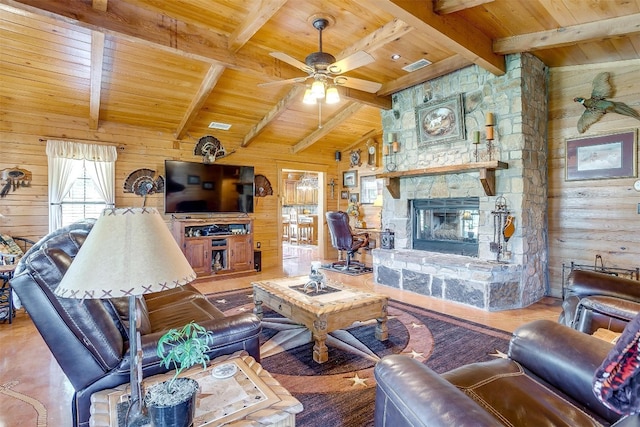 living room with ceiling fan, wood ceiling, wooden walls, and a stone fireplace