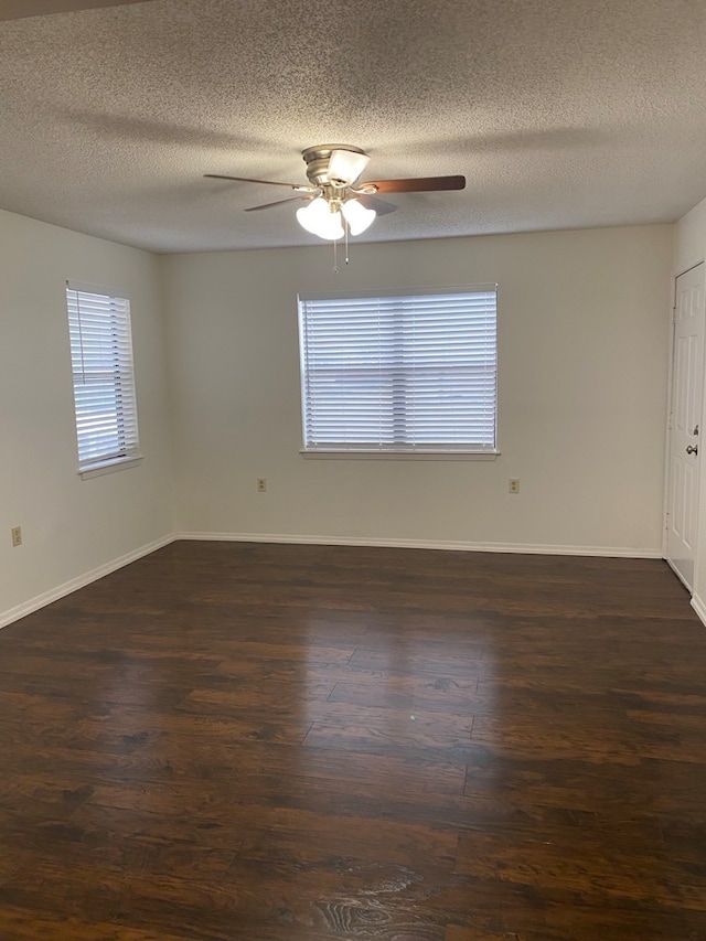 spare room with ceiling fan, a textured ceiling, dark hardwood / wood-style flooring, and a wealth of natural light