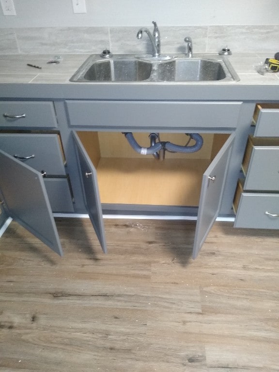 room details with backsplash, sink, and light wood-type flooring