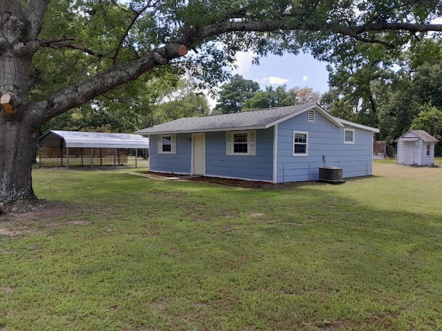 rear view of property featuring a yard, central AC unit, and a storage shed