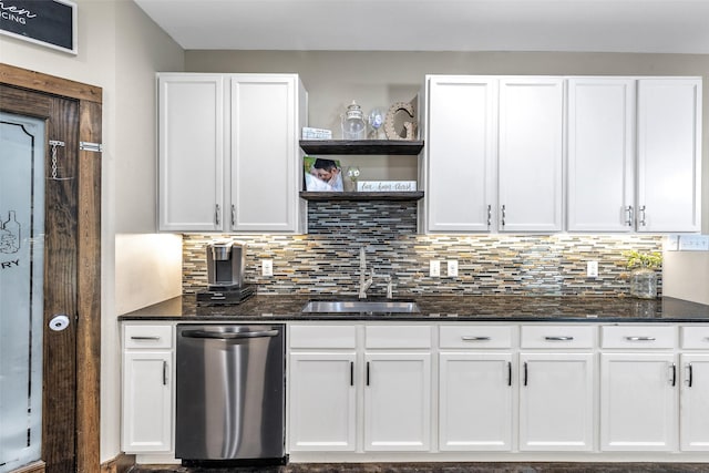 kitchen featuring white cabinetry, tasteful backsplash, dark stone counters, stainless steel dishwasher, and sink