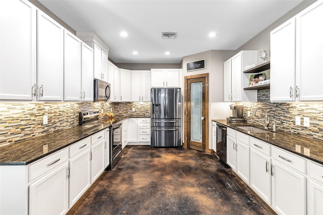 kitchen with stainless steel appliances, decorative backsplash, white cabinetry, sink, and dark stone counters