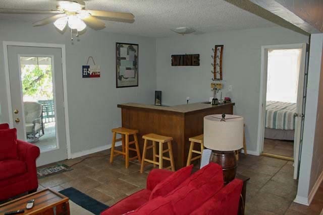 bar with a textured ceiling, a bar, a ceiling fan, and baseboards