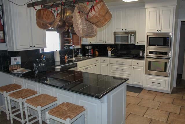 kitchen with a peninsula, white cabinets, and stainless steel appliances