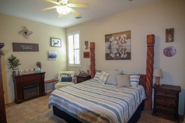 bedroom with a fireplace, visible vents, and a ceiling fan