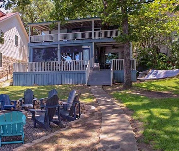 rear view of property with a balcony, a lawn, and a fire pit