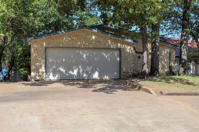 view of front of home with a garage, stone siding, and concrete driveway