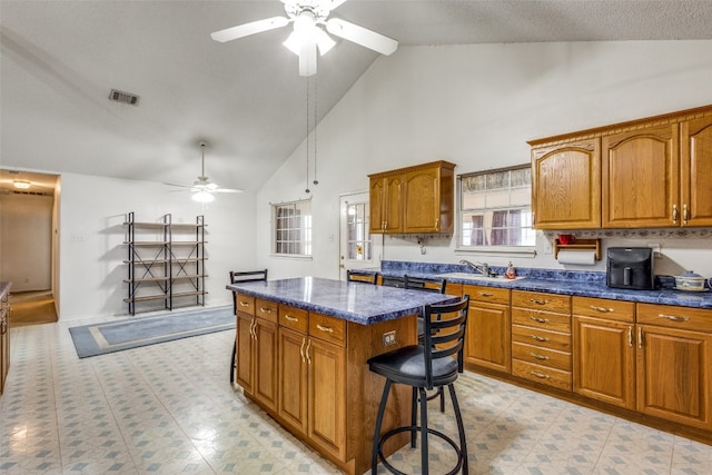 kitchen with a breakfast bar, high vaulted ceiling, a center island, ceiling fan, and sink