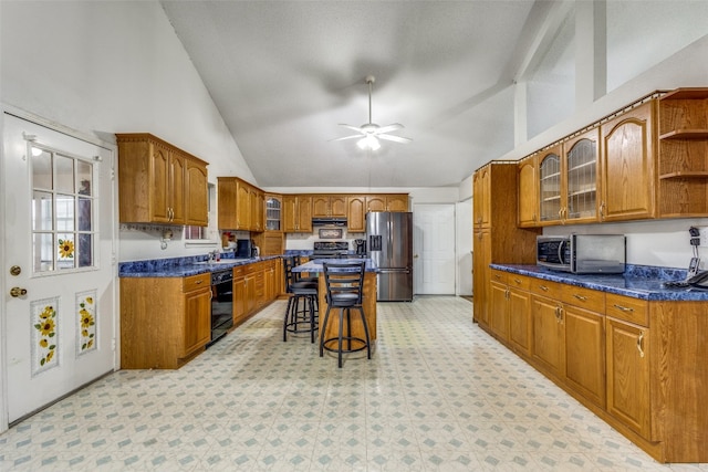 kitchen with high vaulted ceiling, a kitchen bar, ceiling fan, and appliances with stainless steel finishes