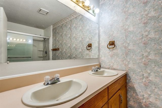 bathroom featuring a textured ceiling, vanity, and a shower with shower door