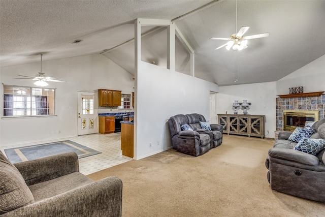 living room featuring light carpet, a tiled fireplace, ceiling fan, and high vaulted ceiling