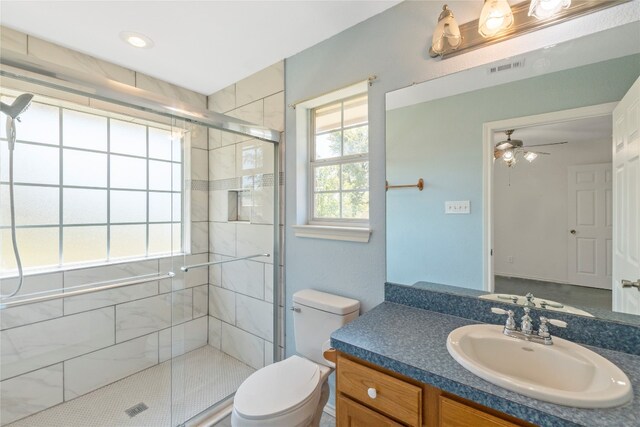 bathroom featuring oversized vanity, toilet, ceiling fan, and a shower with door