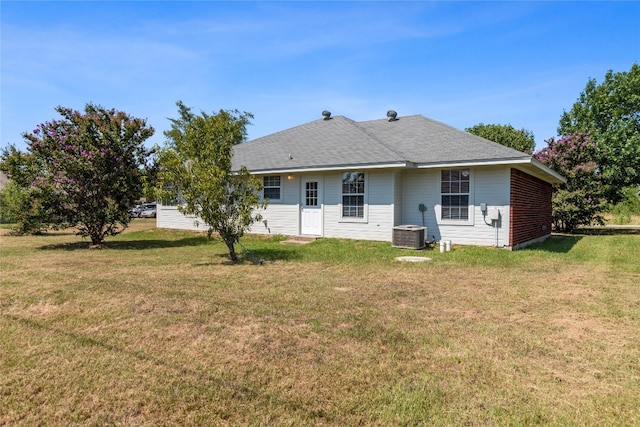 back of property featuring a lawn and central air condition unit