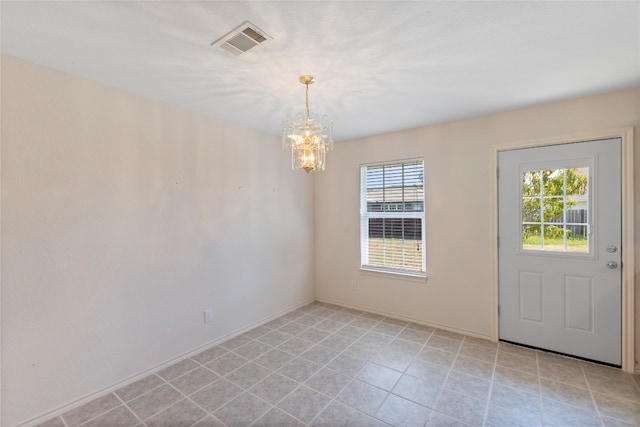 empty room with light tile flooring and a notable chandelier