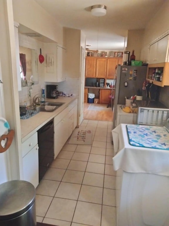 kitchen featuring backsplash, stainless steel fridge, light hardwood / wood-style floors, sink, and black dishwasher