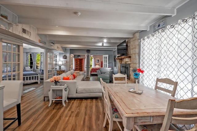 dining area featuring a fireplace, a wealth of natural light, beam ceiling, and hardwood / wood-style flooring