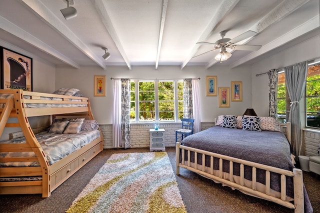 bedroom with a textured ceiling, ceiling fan, dark carpet, and beamed ceiling