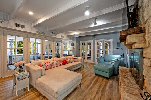 living room with beamed ceiling, hardwood / wood-style floors, french doors, and a fireplace