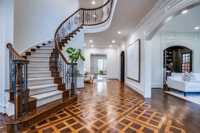 entryway featuring crown molding, a towering ceiling, and french doors