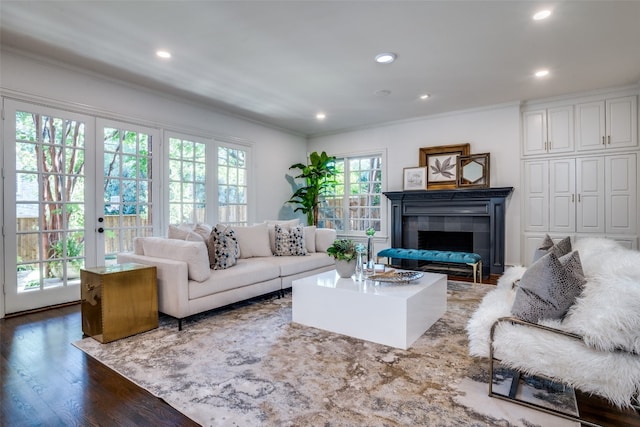 living room featuring a tiled fireplace, french doors, dark wood-type flooring, and ornamental molding