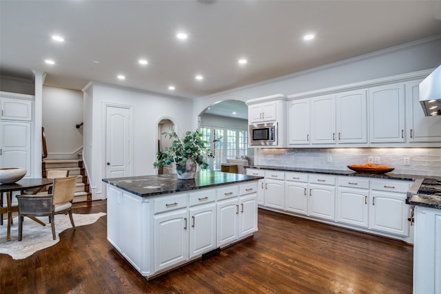 kitchen featuring dark hardwood / wood-style flooring, stainless steel microwave, a kitchen island, and white cabinets