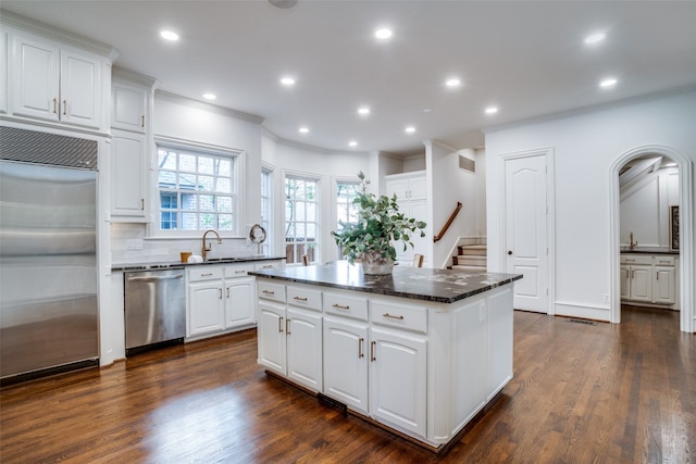 kitchen with backsplash, stainless steel appliances, white cabinets, a center island, and dark hardwood / wood-style flooring