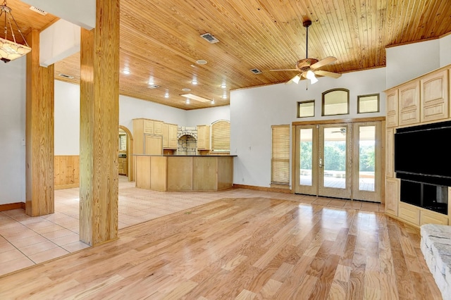 unfurnished living room with light hardwood / wood-style flooring, ceiling fan, a towering ceiling, and wooden ceiling