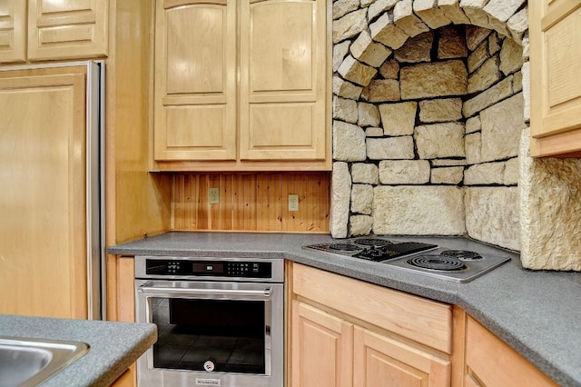 kitchen featuring backsplash, light brown cabinetry, and stainless steel appliances