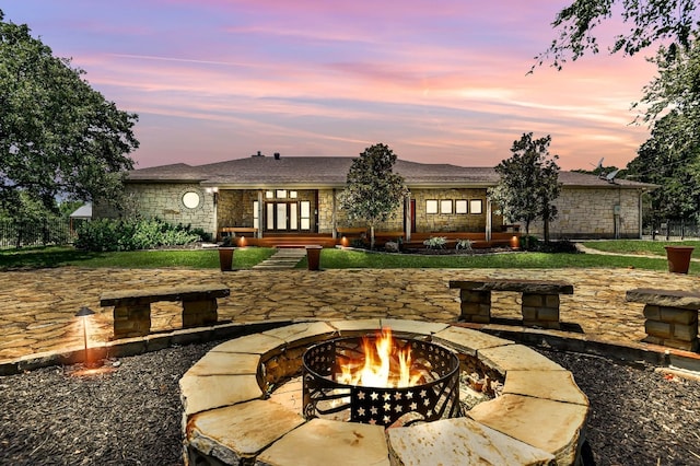 back house at dusk with a patio area, a fire pit, and french doors