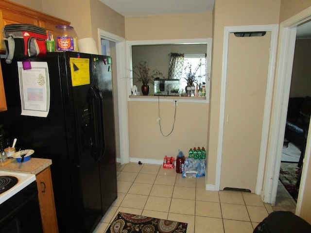 kitchen featuring light tile floors, range, and black fridge