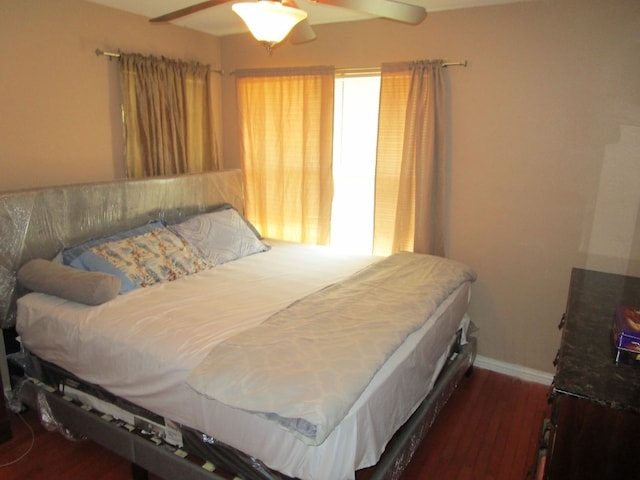 bedroom featuring dark hardwood / wood-style floors, ceiling fan, and multiple windows