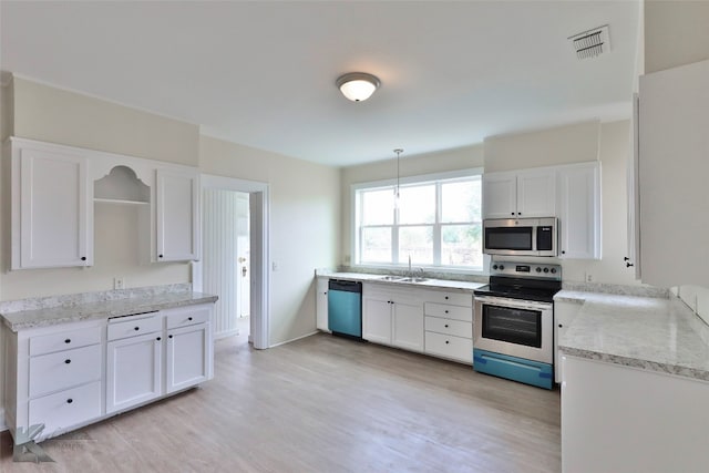 kitchen with white cabinets, stainless steel appliances, and light hardwood / wood-style flooring