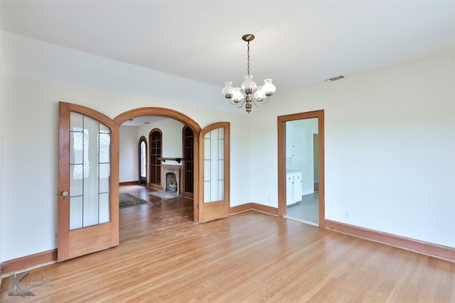 spare room featuring light hardwood / wood-style flooring and a notable chandelier