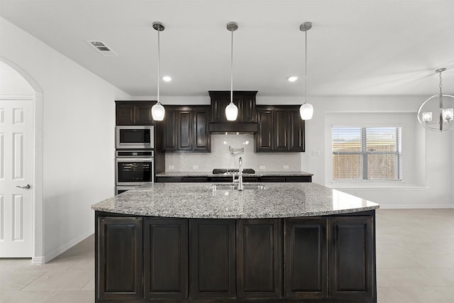 kitchen with light stone countertops, decorative light fixtures, stainless steel appliances, an inviting chandelier, and light tile floors