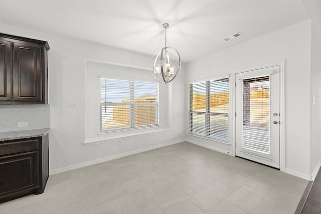 unfurnished dining area with a healthy amount of sunlight, light tile floors, and a chandelier