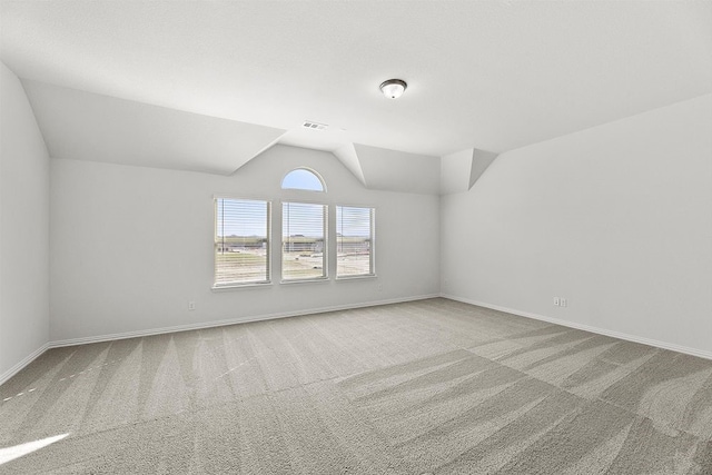 unfurnished room featuring light colored carpet and vaulted ceiling