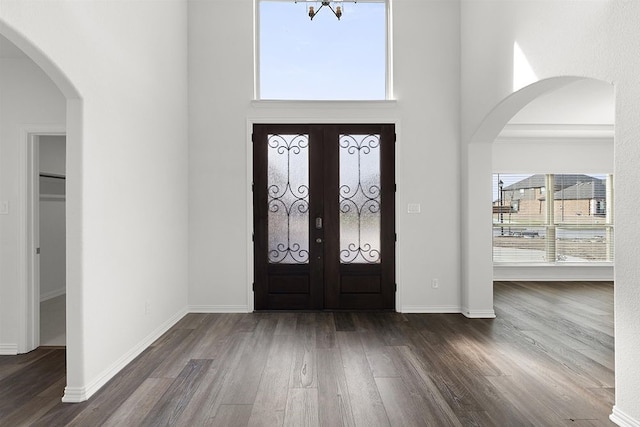 foyer with french doors, dark wood-type flooring, and a chandelier