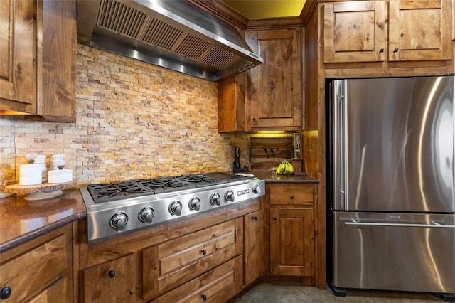 kitchen featuring backsplash, dark stone countertops, appliances with stainless steel finishes, and wall chimney range hood