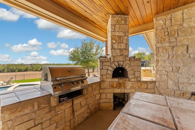 view of terrace featuring an outdoor kitchen, area for grilling, and an outdoor stone fireplace