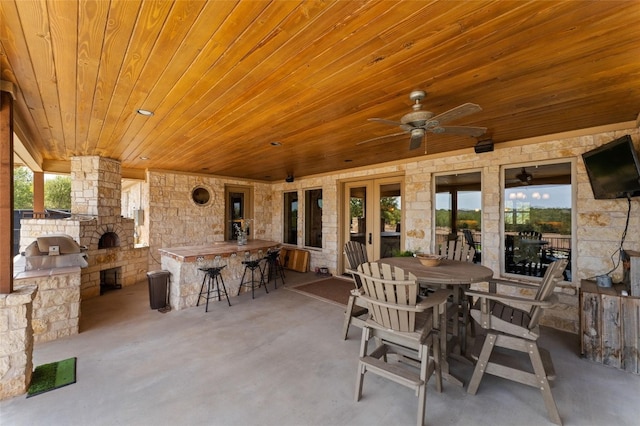 view of patio with a bar, ceiling fan, and exterior kitchen