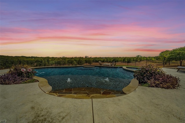 pool at dusk with a patio and pool water feature