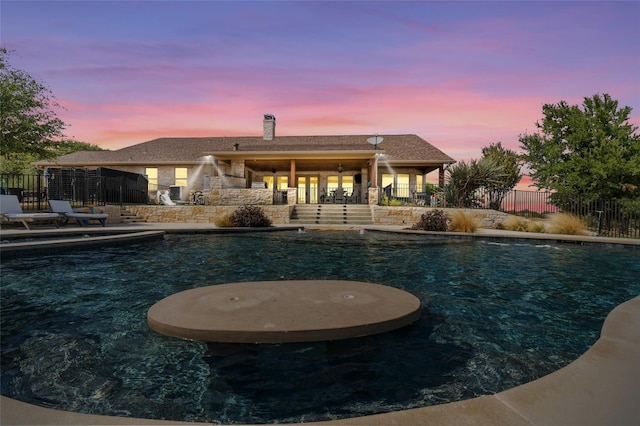 pool at dusk featuring a patio